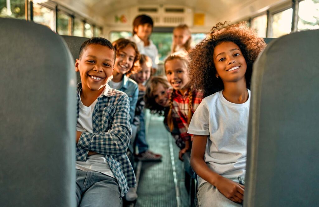Smiling students sitting inside a school bus.