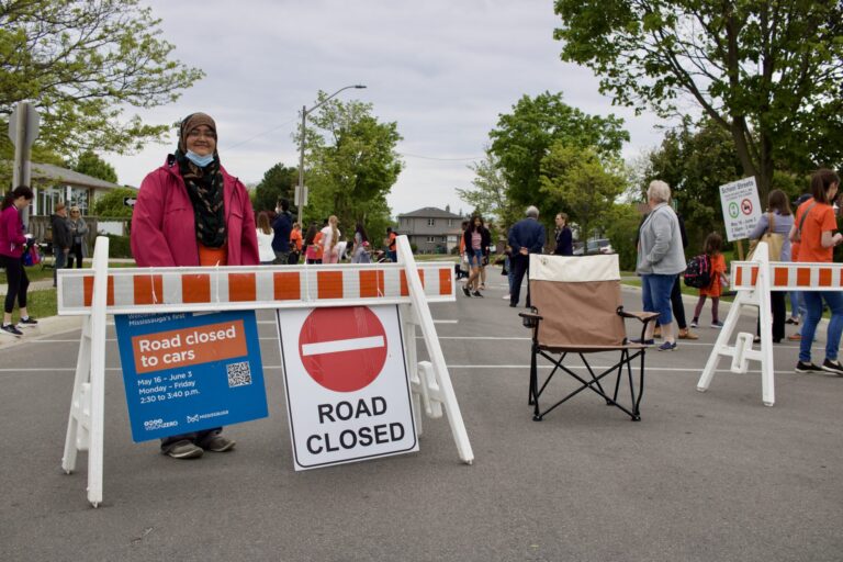 A woman posing in front of a Road Closed sign set up at a School Street