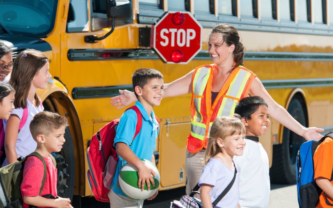 Kids guided out of a school bus by a crossing guard