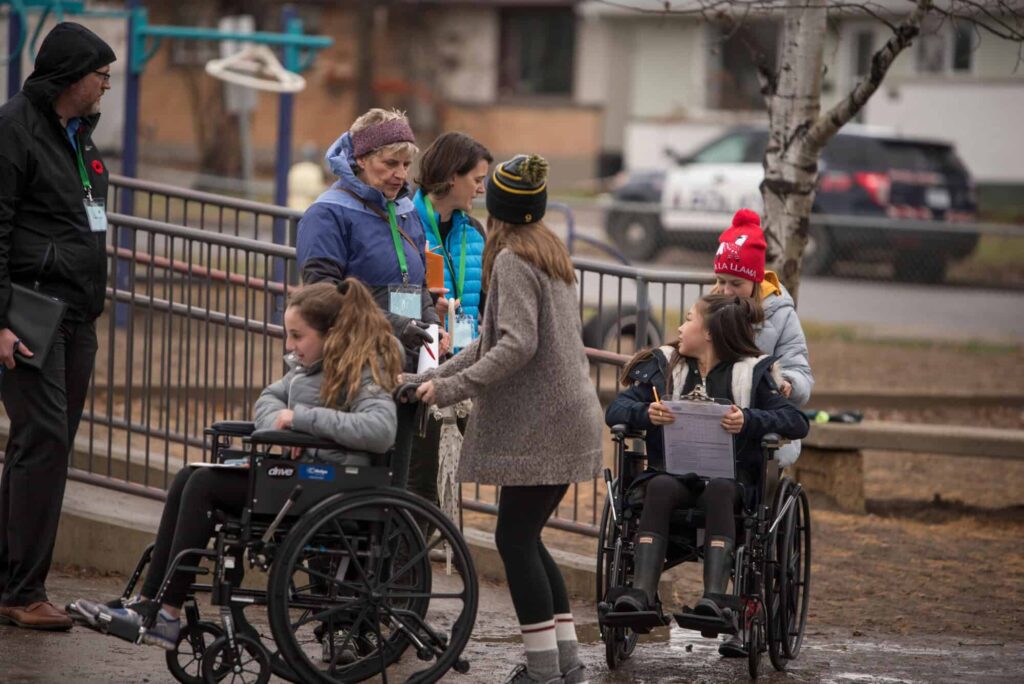 Students on wheelchair being wheeled to school by friends