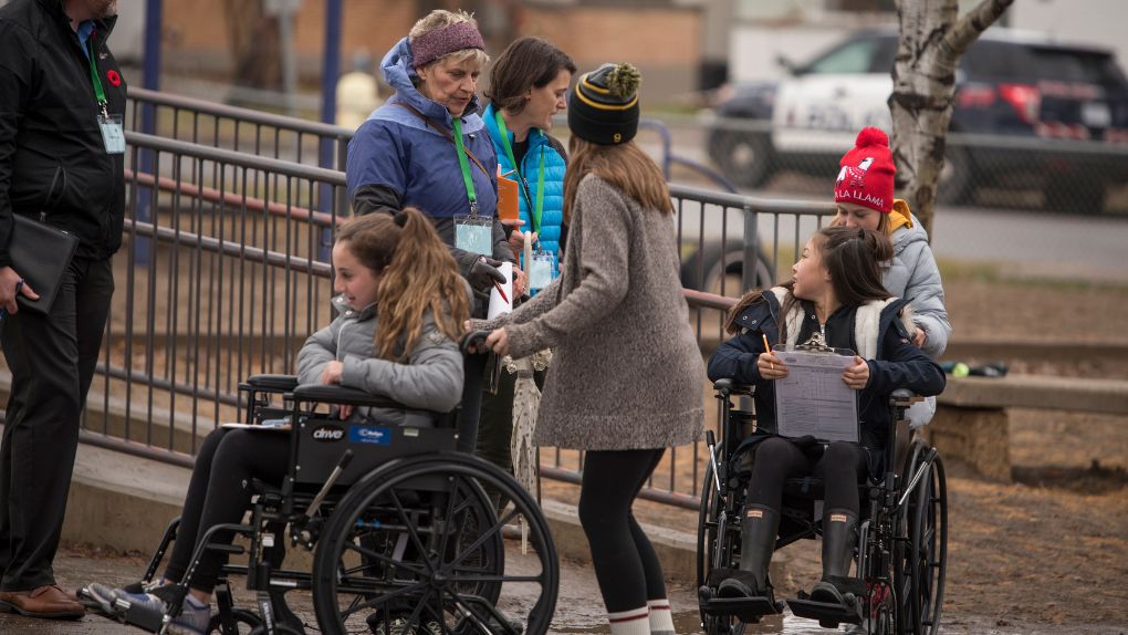 Students on wheelchair being wheeled to school by friends