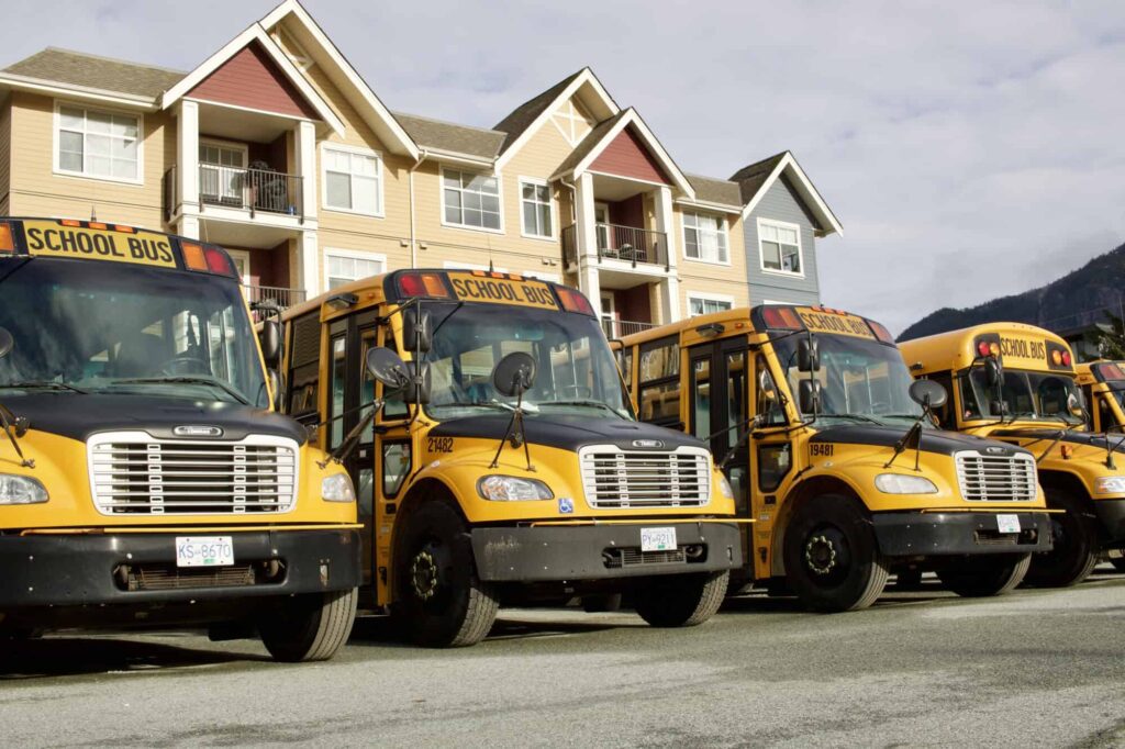 parked buses in front of a house or school.