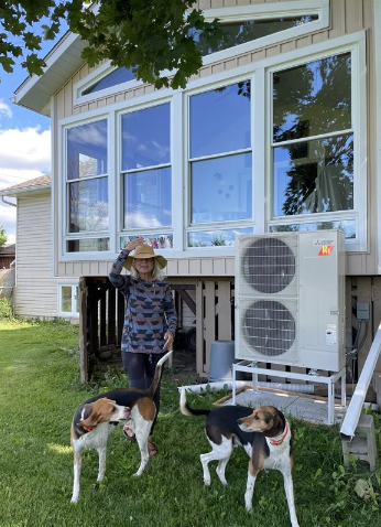 Woman and 2 dogs standing next to a heat pump.