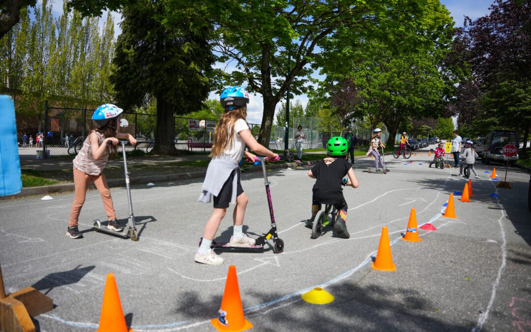 Children riding scooters in a sectioned off area of the street.