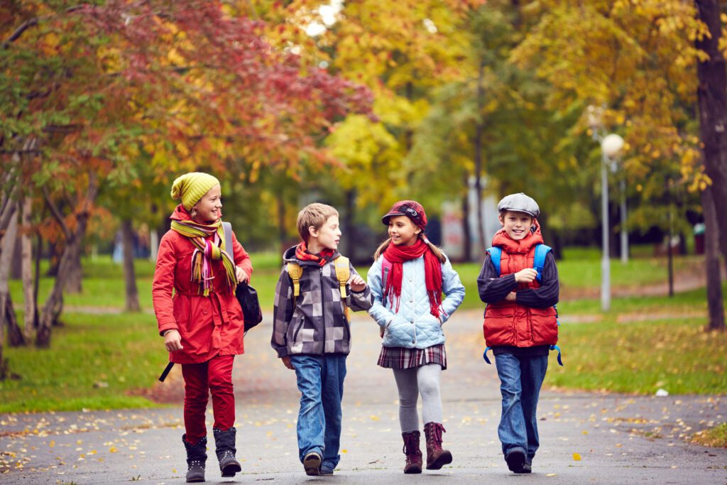 Group of children walking in the fall on a paved trail through a park