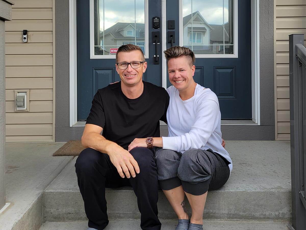 People (Huckabay and Caron) sitting on the front steps of their newly retrofit home.