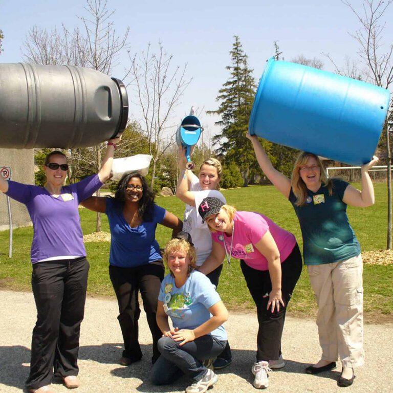 group of people. two people holding up rain barrels