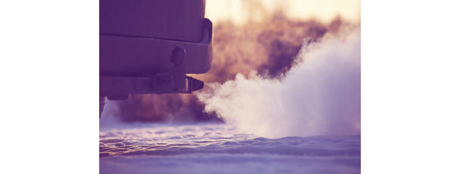 Close-up of a car’s exhaust pipe releasing a cloud of white exhaust.