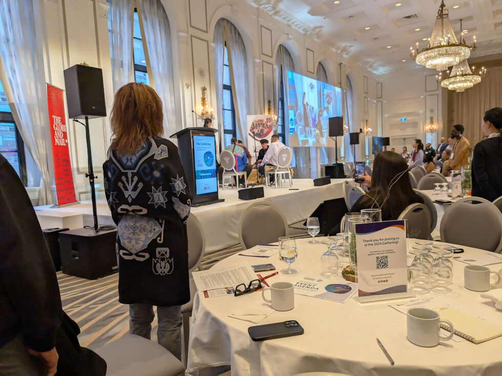People gathered in a banquet hall watching Indigenous drummers and the drum ceremony.