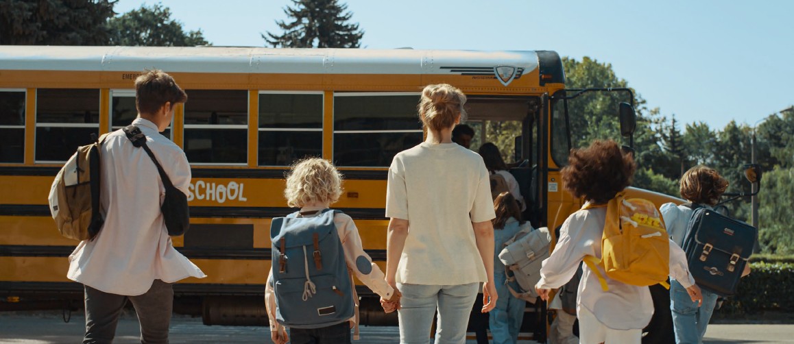 Children and caregivers walking towards a school bus.