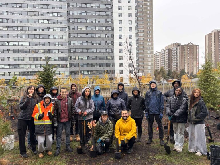 Group of people smiling in the rain after planting a new mini forest on university of ottawa campus