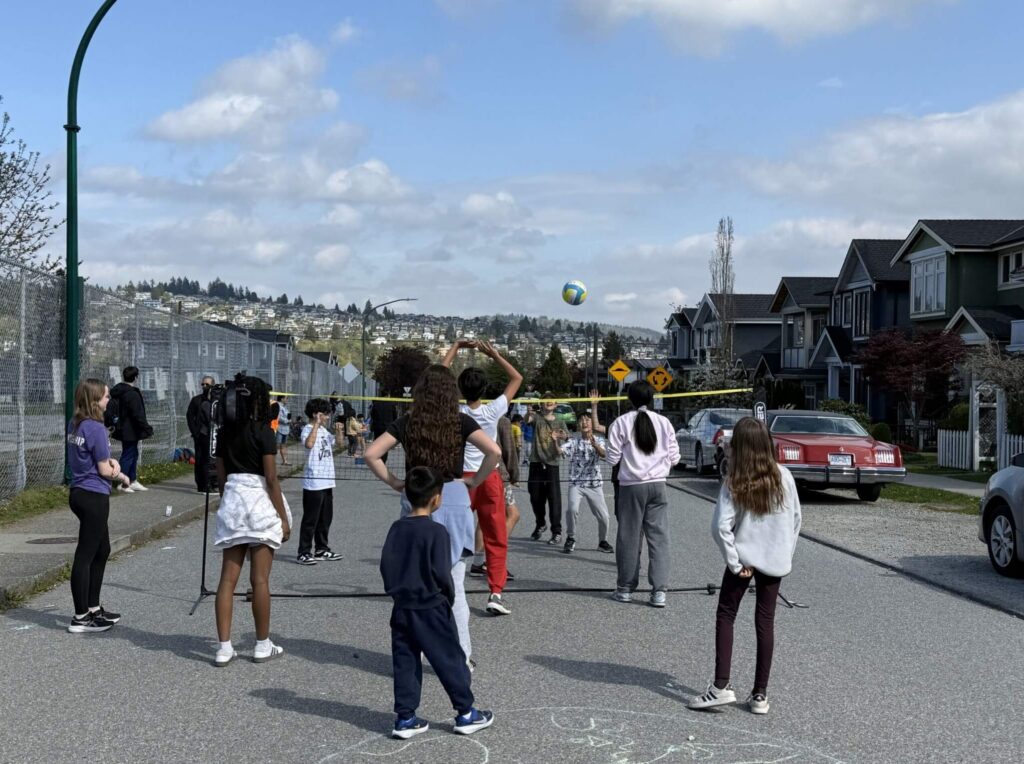 Children playing volleyball on a temporarily pedestrianized street in front of their school.
