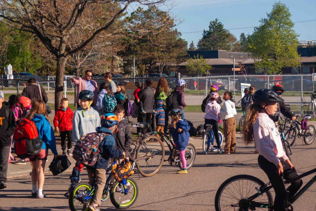 Dozens of children enjoy cycling and playing games on a pedestrianized street in front of their school.