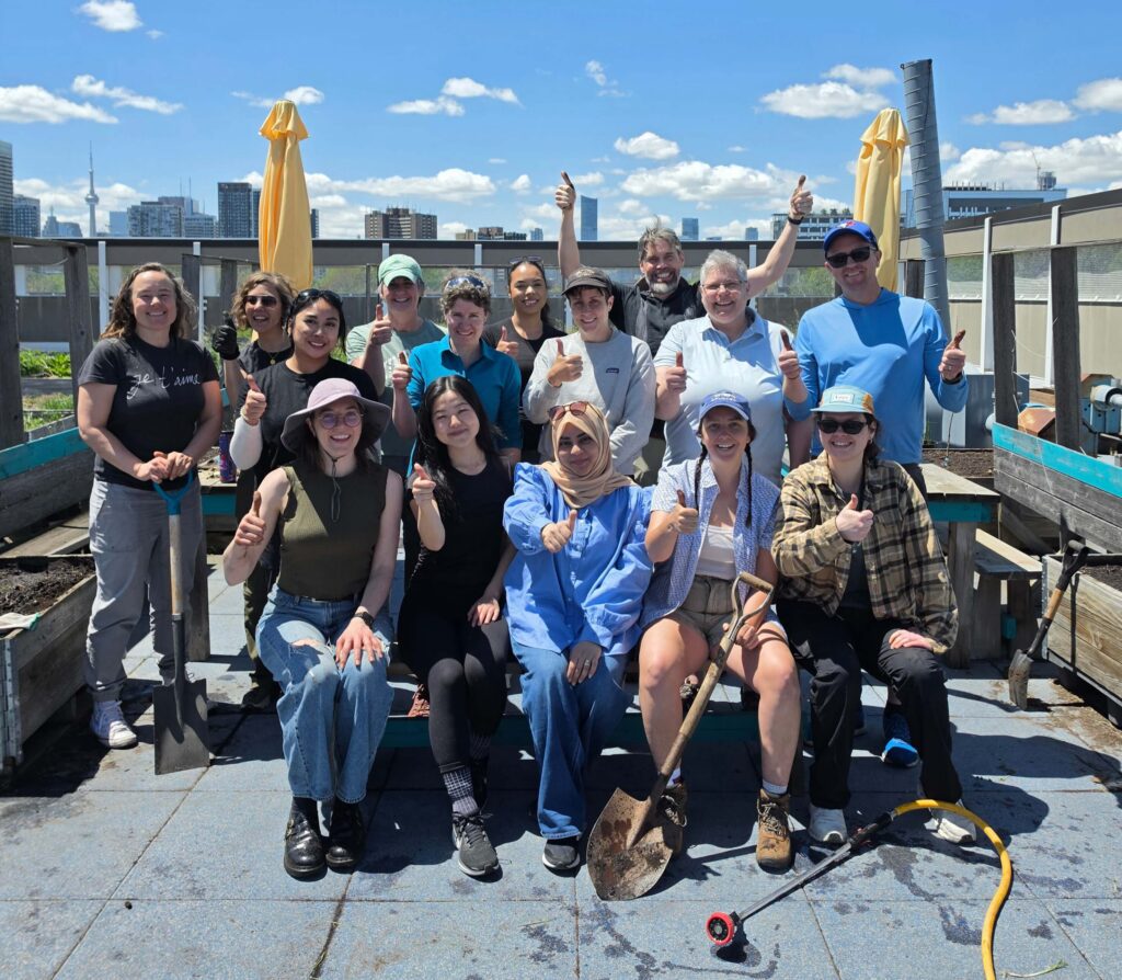 Group photo of the staff team at Green Communities Canada holding up their thumbs after planting a community garden.