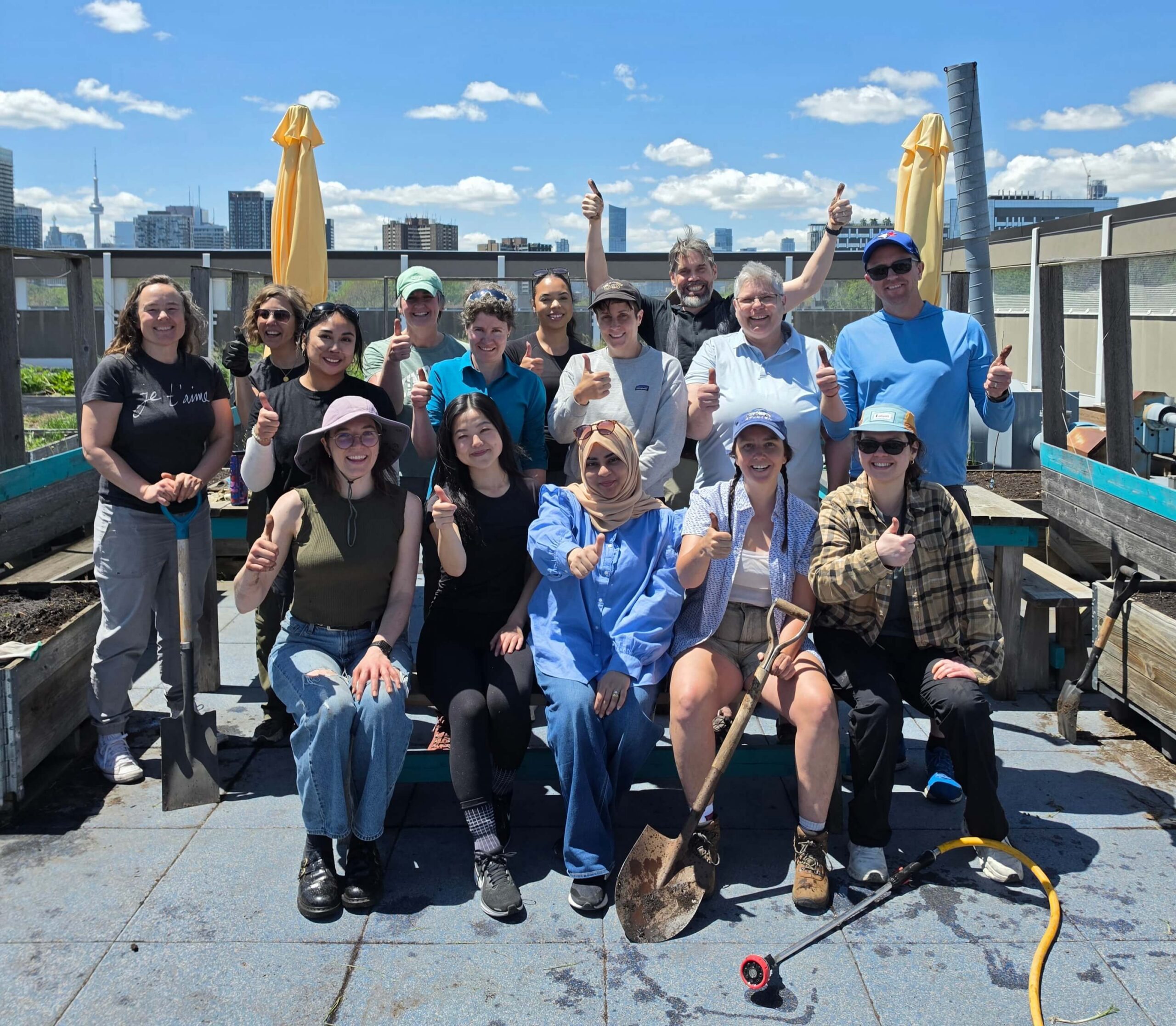 Group photo of the staff team at Green Communities Canada holding up their thumbs after planting a community garden.