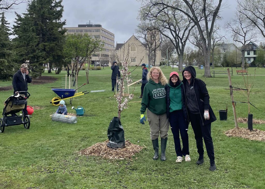 Volunteers posing beside newly planted trees during a community tree planting event.